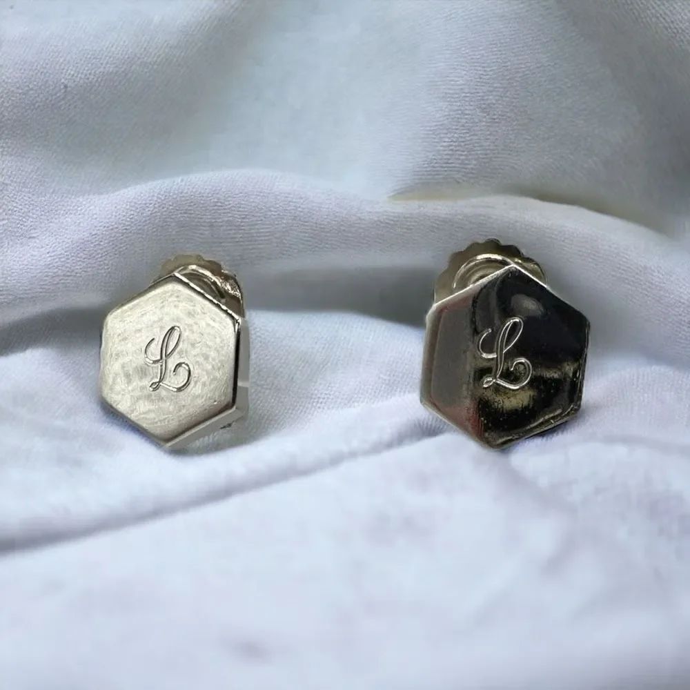 CORO silver toned hexagon shaped clip on earrings with the letter L